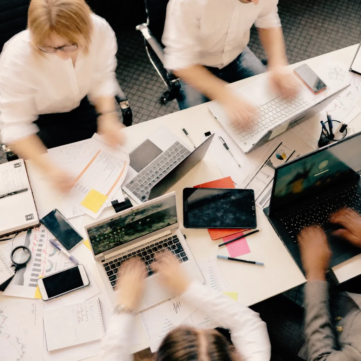A team working together around a table of laptops and notes